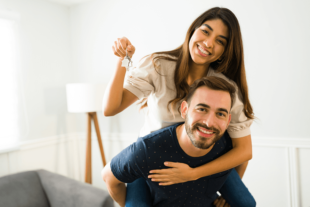 A couple holding the keys to their newly purchased home with a high ratio insured mortgage.