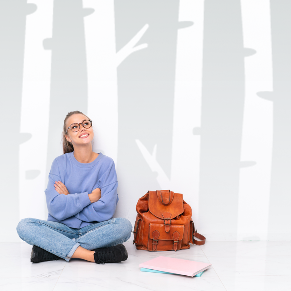 A young student sitting beside her backpack, arms crossed, smiling, reflecting no account fees at Northern Birch
