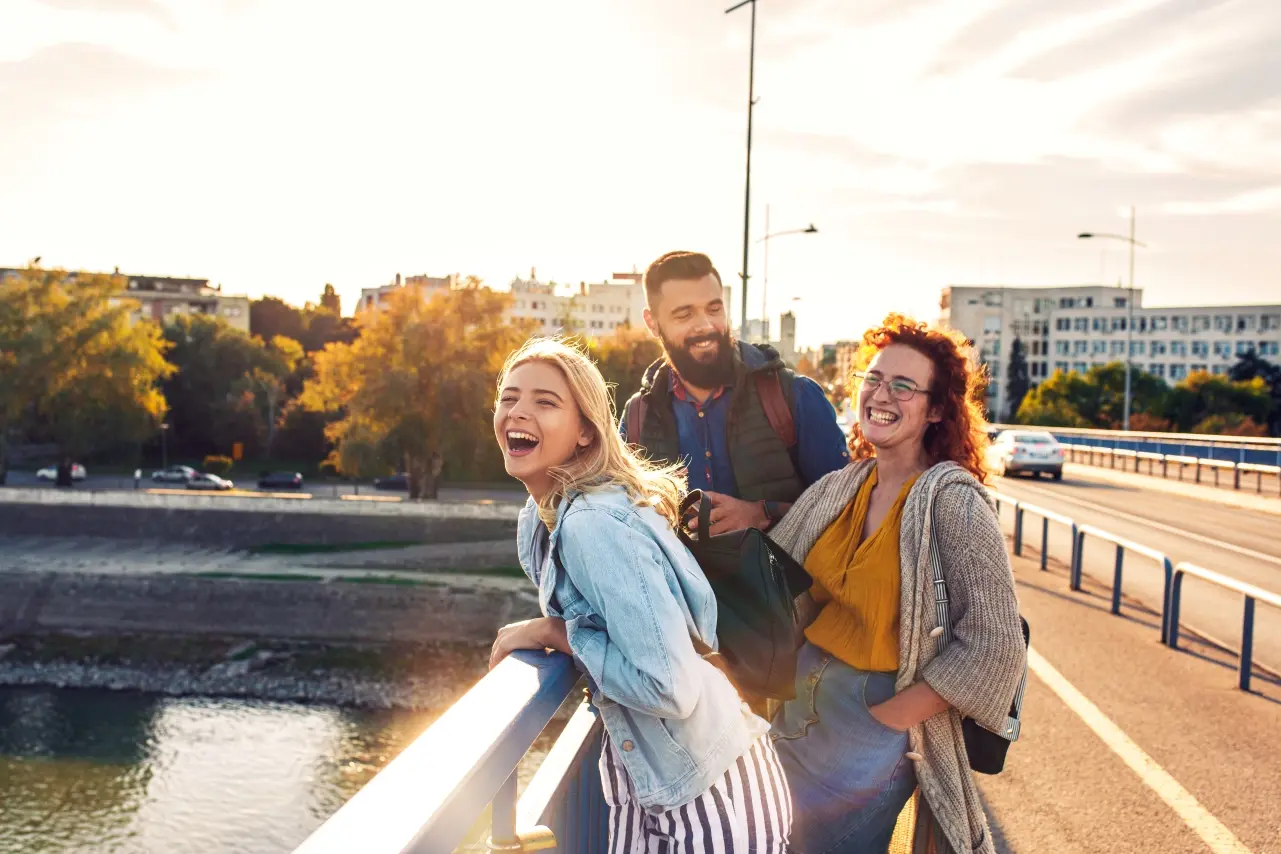 Students out for walk on a bridge overlooking a river having a good time.