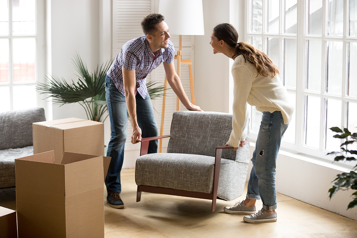 A couple moving furniture in a new co-op or co-ownership property