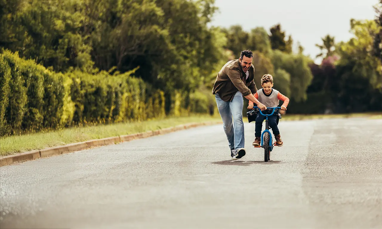 A dad teaching his son to ride a bike, reflecting secure investing